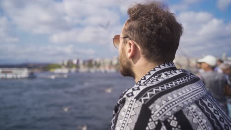 Young-man-looking-at-seagulls-by-the-sea.